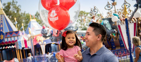  A father holding daughter with balloon at Disney.