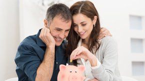 A couple puts money into a piggy bank.